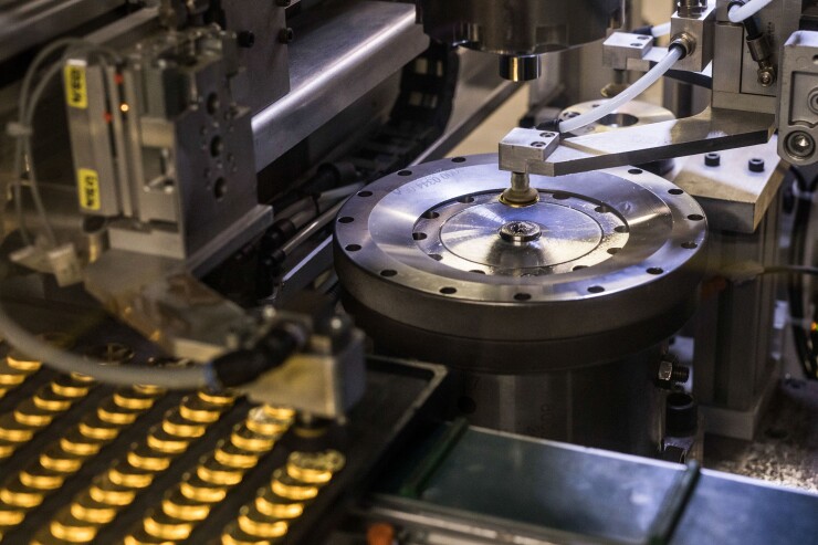 A coin press stamps gold bullion coins during their production at Britain's Royal Mint.
