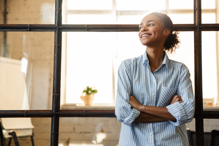 Woman leaning back against table with arms folded, smiling