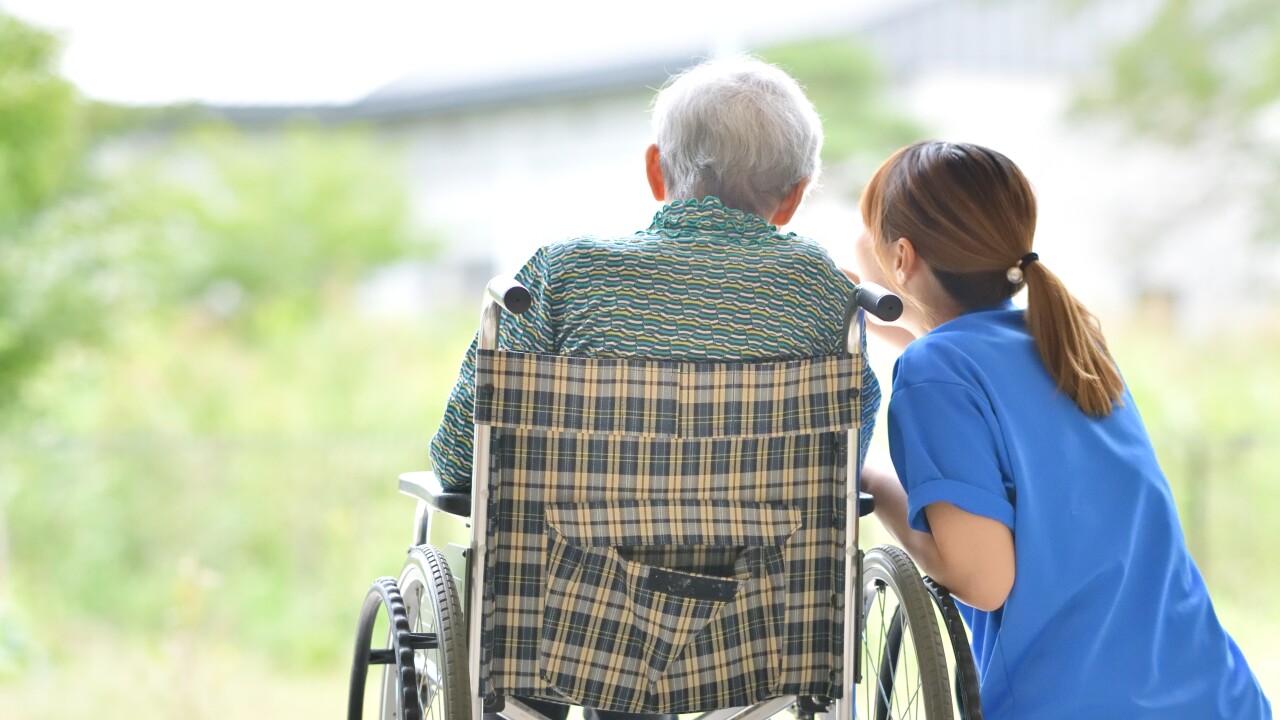 A caretaker talks to a person in a wheelchair.