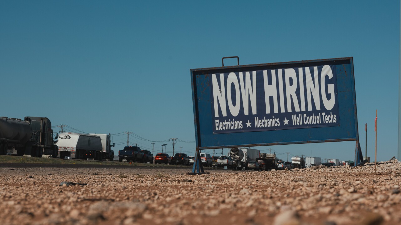 A sign on a dirt road reads, "Now Hiring."