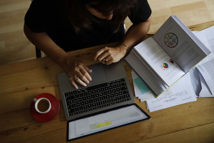 A woman works at an Apple Inc. laptop computer on a dining room table in this arranged photograph taken in Bern, Switzerland, on Wednesday, Aug. 19, 2020. The biggest Wall Street firms are navigating how and when to bring employees safely back to office buildings in global financial hubs, after lockdowns to address the Covid-19 pandemic forced them to do their jobs remotely for months. Photographer: Stefan Wermuth/Bloomberg