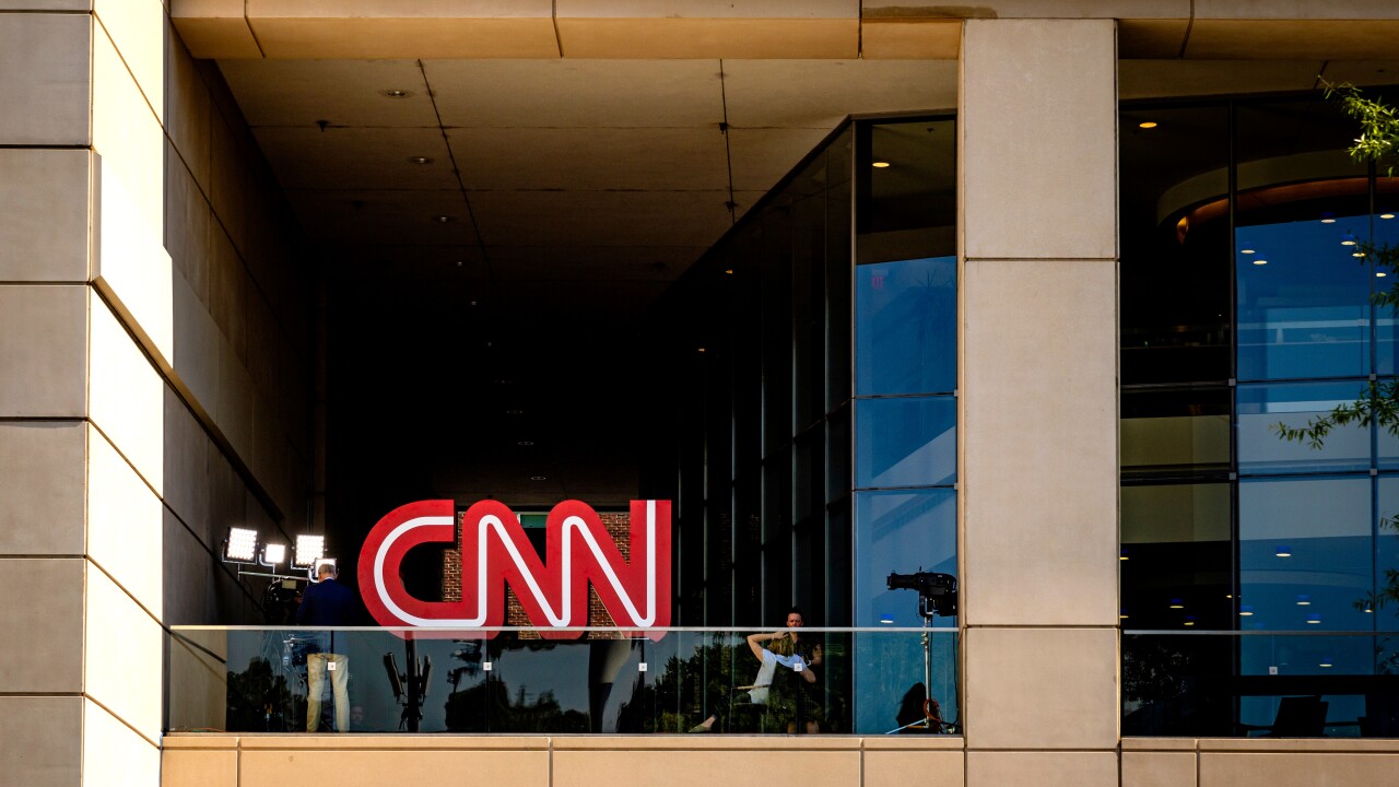 CNN logo (the words CNN in red with a white line in the middle of said words) at the top of a building during the day.