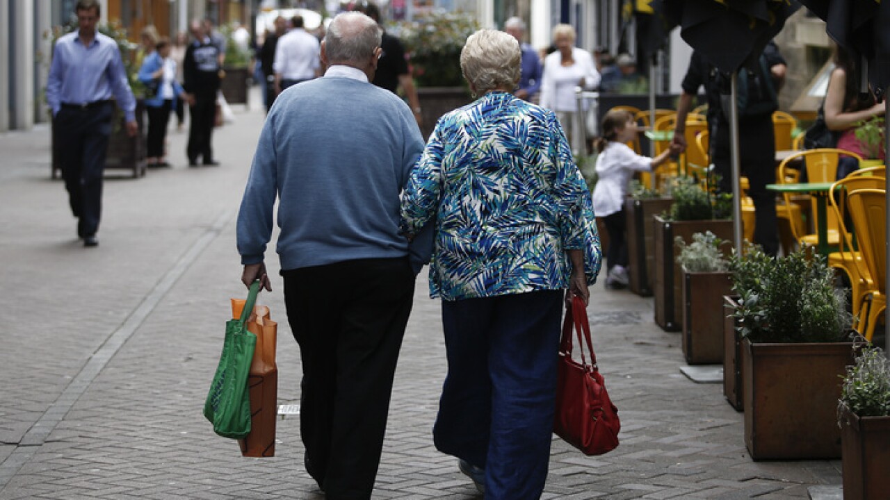 An elderly couple walk arm-in-arm past an outdoor cafe terrace in Edinburgh, U.K., on Wednesday, July 31, 2013. The latest opinion polls show supporters of Scottish First Minister Alex Salmond's campaign for independence lagging behind those in favor of the status quo by more than 20 percentage points ahead of the Sept.18, 2014, referendum. Photographer: Simon Dawson/Bloomberg