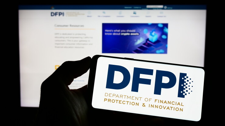 Stuttgart, Germany - 04-23-2023: Person holding mobile phone with logo of Californian department DFPI on screen in front of web page. Focus on phone display.