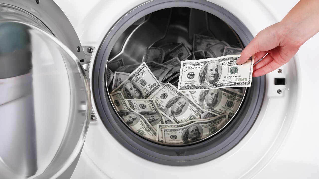 Female putting money into washing machine, closeup