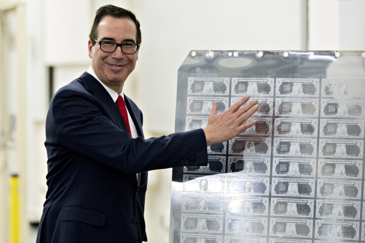 U.S. Treasury Secretary Steven Mnuchin gestures while standing next to a printing plate for $1 dollar notes bearing Mnuchin's name at the U.S. Bureau of Engraving and Printing in Washington, D.C.
