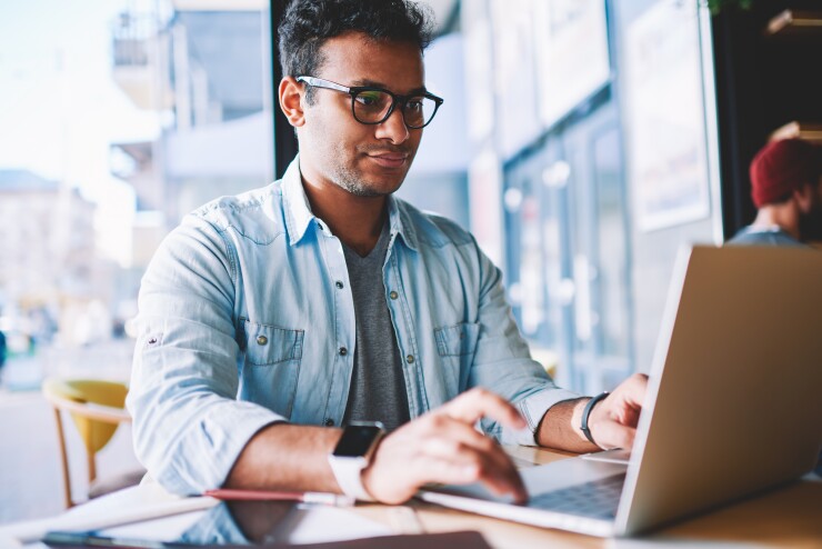Man works on laptop from public area table