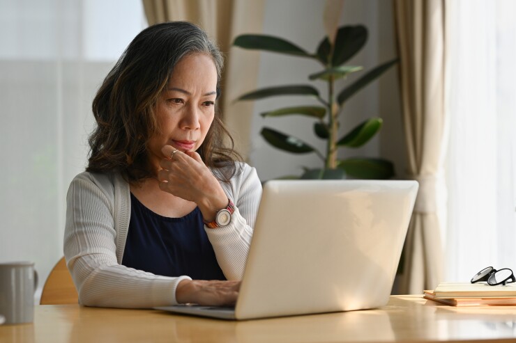 Woman looking at laptop with hand on chin