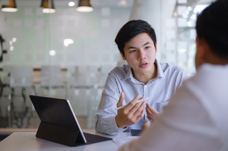 Man speaking to someone across the table from him.
