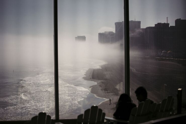 People look out a window at the beach as fog moves in over the shore in Atlantic City, New Jersey, U.S., on Monday, May 2, 2016.