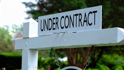 Under contract sign on wooden post. Real estate business.