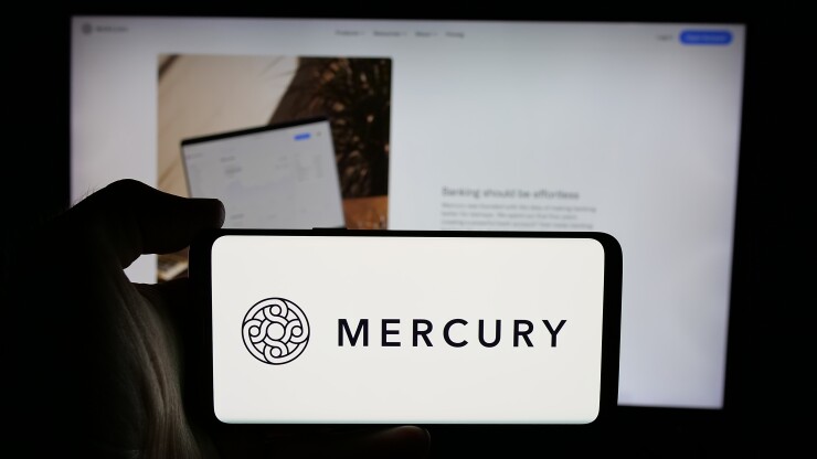 Stuttgart, Germany - 10-31-2024: Person holding cellphone with logo of US fintech company Mercury Technologies Inc. on screen in front of business webpage. Focus on phone display.