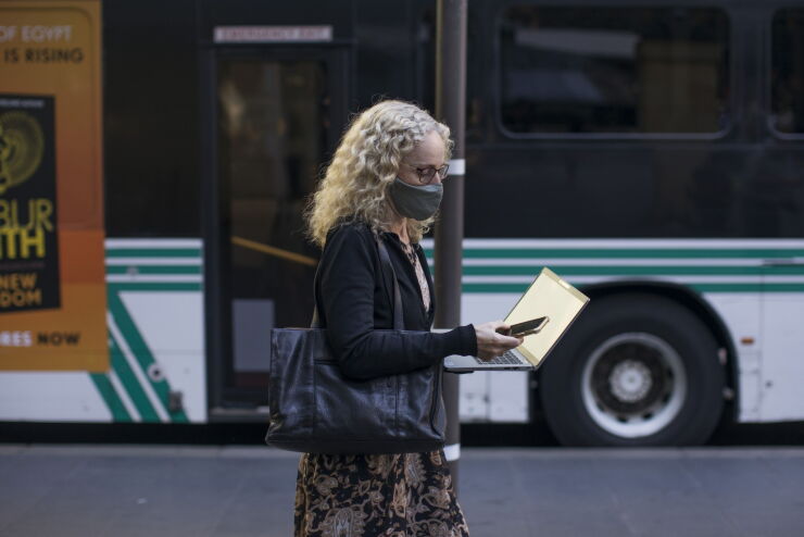 A pedestrian looks at a smartphone and laptop in a street in Sydney, Australia, on Wednesday, Dec. 15, 2021. Australian household sentiment declined this month as concerns mounted about the new omicron variant of coronavirus in the nation's recently re-opened eastern states of New South Wales and Victoria. Photographer: Brent Lewin/Bloomberg