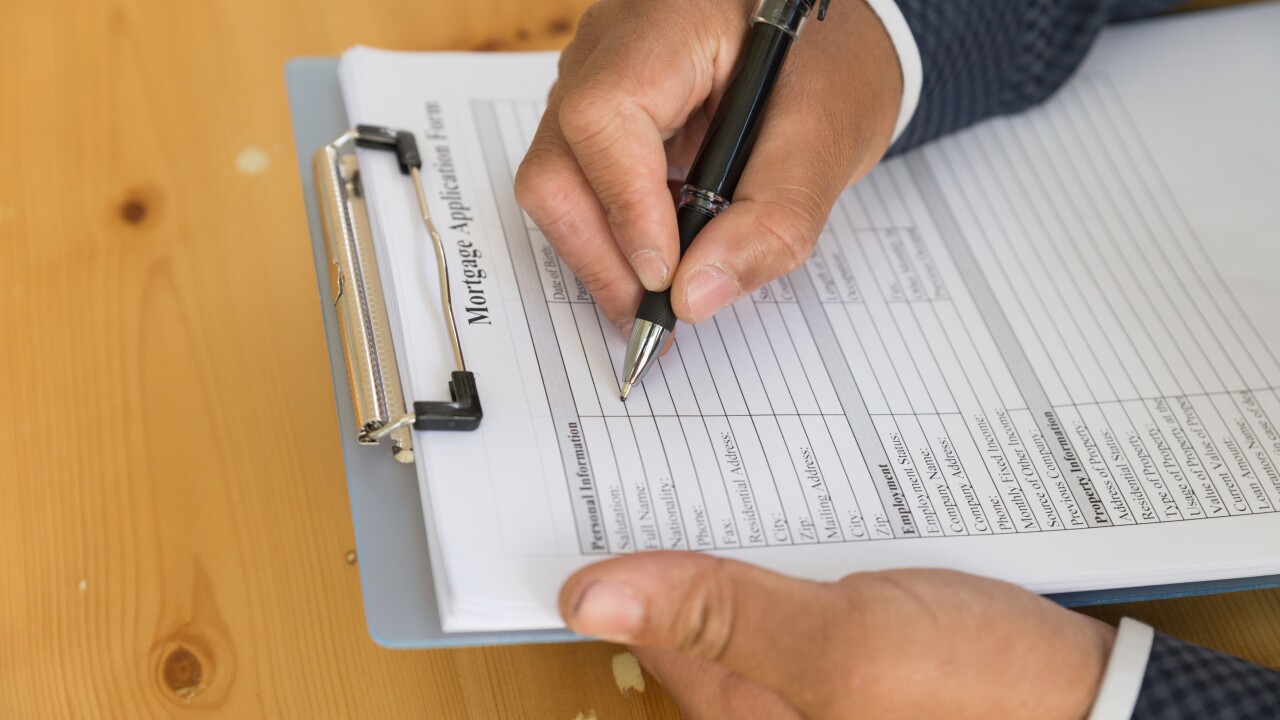 hand fill out mortgage loan application on a clipboard. A form t