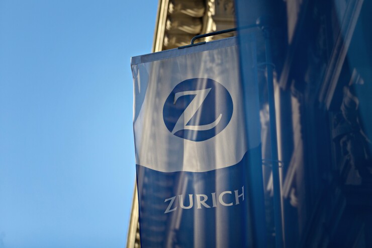 A flag on a building that has the Zurich logo and reads Zurich.