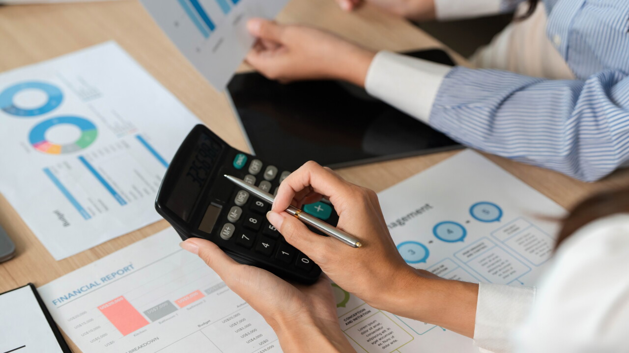 Calculating Financial Metrics. Professionals using a calculator for financial analysis and reports.
