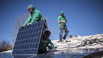 SolarCity Corp. workers secure solar panels to a rooftop