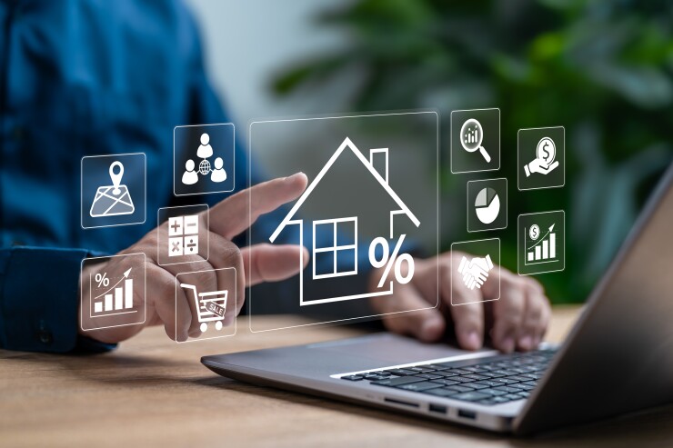 A person using a laptop with a holographic image of a house and a percentage sign.