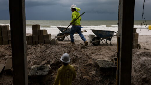 Workers haul sand near home under renovation following damage from Hurricane Ian in Fort Myers Beach, Florida