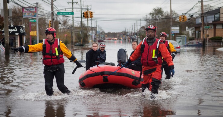 Members of the Fire Department of New York (FDNY) help residents make their way to dry ground on Hylan Boulevard in the Staten Island borough of New York, U.S., on Tuesday, Oct. 30, 2012. 