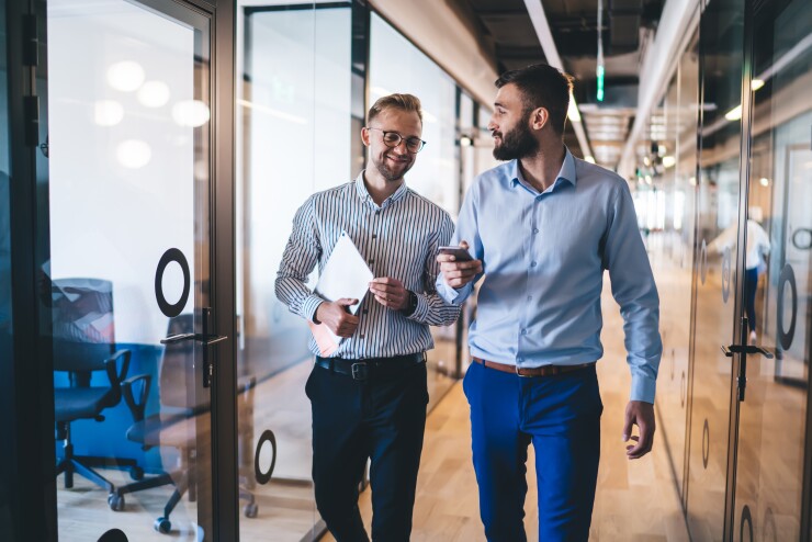 Two men walking in office talking