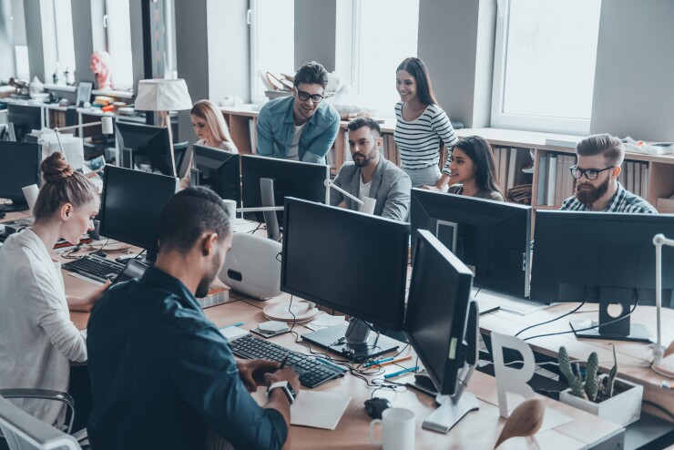 A group of people working on monitors in an office