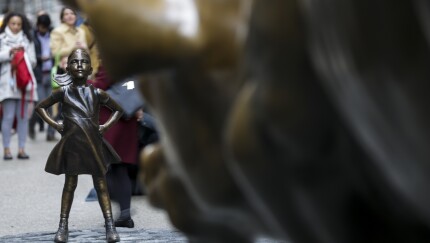 The Fearless Girl statue faces down the Charging Bull sculpture in the Financial District of New York.