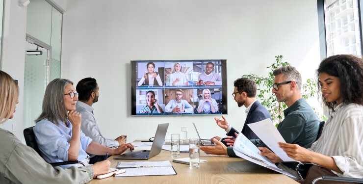 Group meeting in conference room with attendees on screen