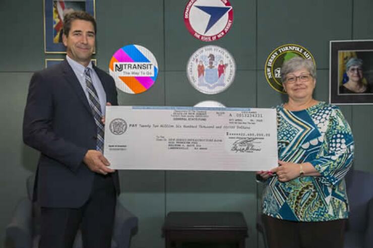 NJDOT Commissioner Diane Gutierrez-Scaccetti presents New Jersey Infrastructure Bank Vice-Chairman Robert Briant Jr. with a $22.6 million check to mark the launch of the state's new transportation loan program.