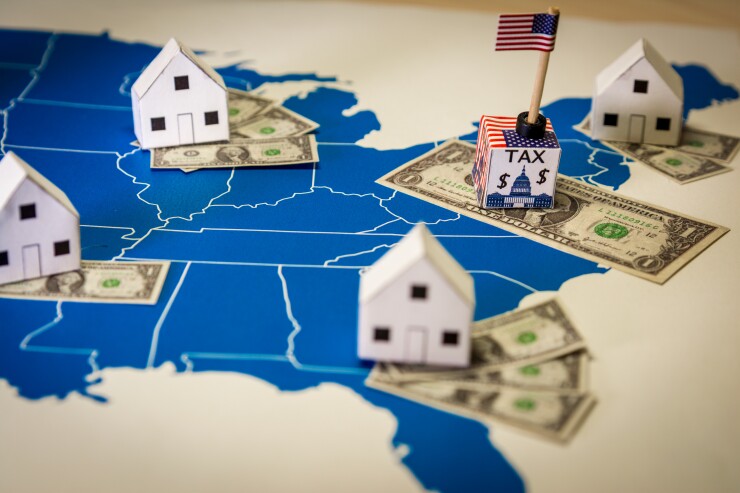 A map of the United States with paper houses and miniature dollar bills placed on various states.