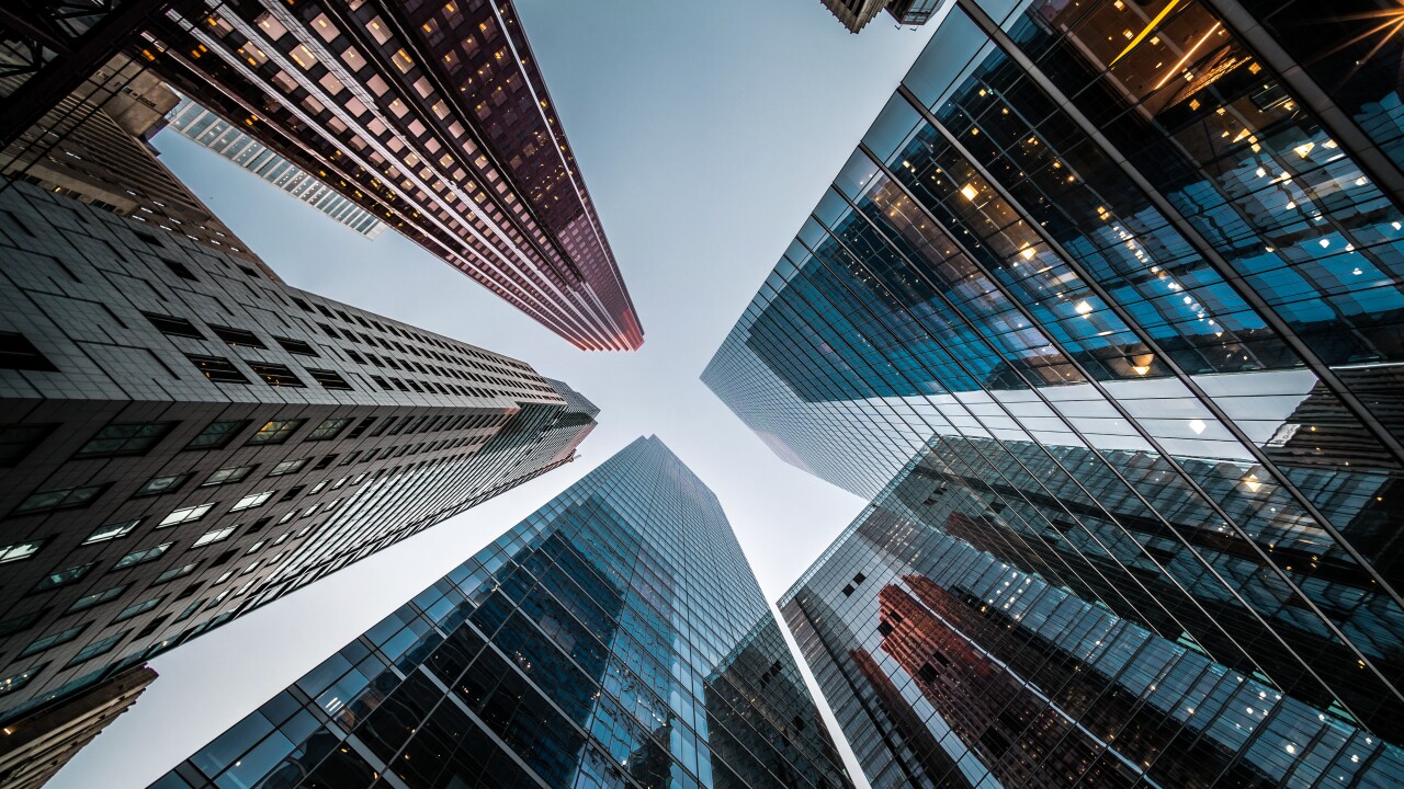 Looking up at high rise office buildings and the sky.