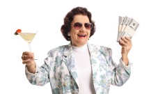 Happy senior woman holding cocktail and money