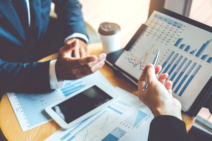 The arms and hands of two people sitting at a table looking at charts