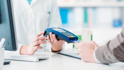 Man's hand holding credit card near machine, paying for doctor visit