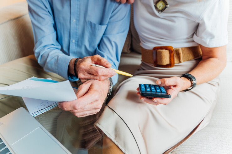 Elderly couple managing household finances and retirement planning, calculating expenses and reviewing bills on a laptop, stressing budget and financial consulting for seniors.