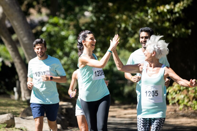 Group of runners with numbers on shirts; women high-fiving