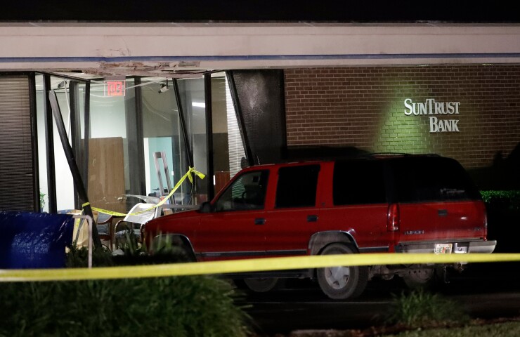 A red SUV is seen parked outside the damaged SunTrust bank early Thursday, Jan. 24, 2019, in Sebring, Fla. Authorities say five customers were shot and killed at the bank on Wednesday.