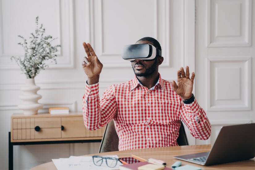 Concentrated Afro american businessman using VR headset, experiencing virtual reality playing game