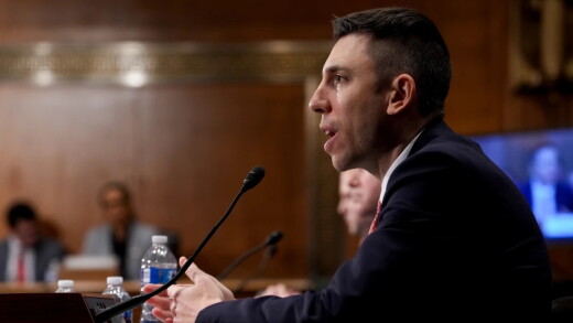 FDIC Chair Travis Hill speaks into a microphone at a congressional hearing.
