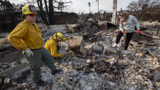 Firefighters from Washington state help a woman and her friends sift through the remains of her family home in the Pacific Palisades area of Los Angeles