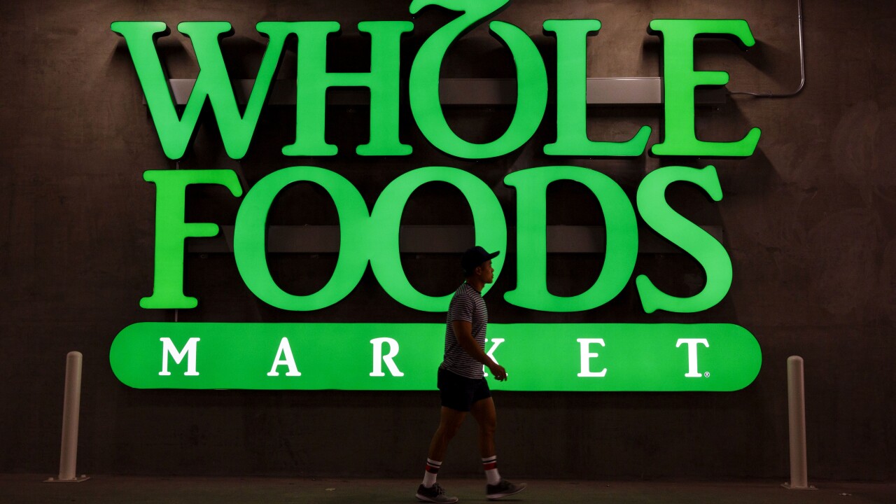 A pedestrian walks past Whole Foods Market signage outside a store in downtown Los Angeles.