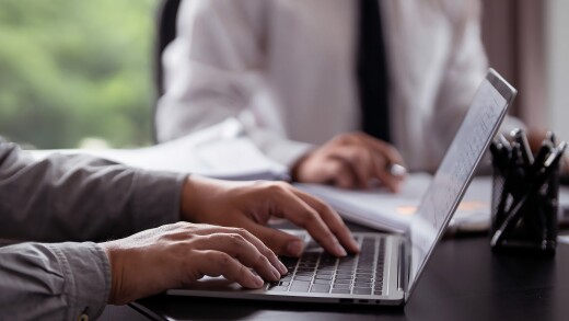 People running property investment calculations and typing on laptop computers.