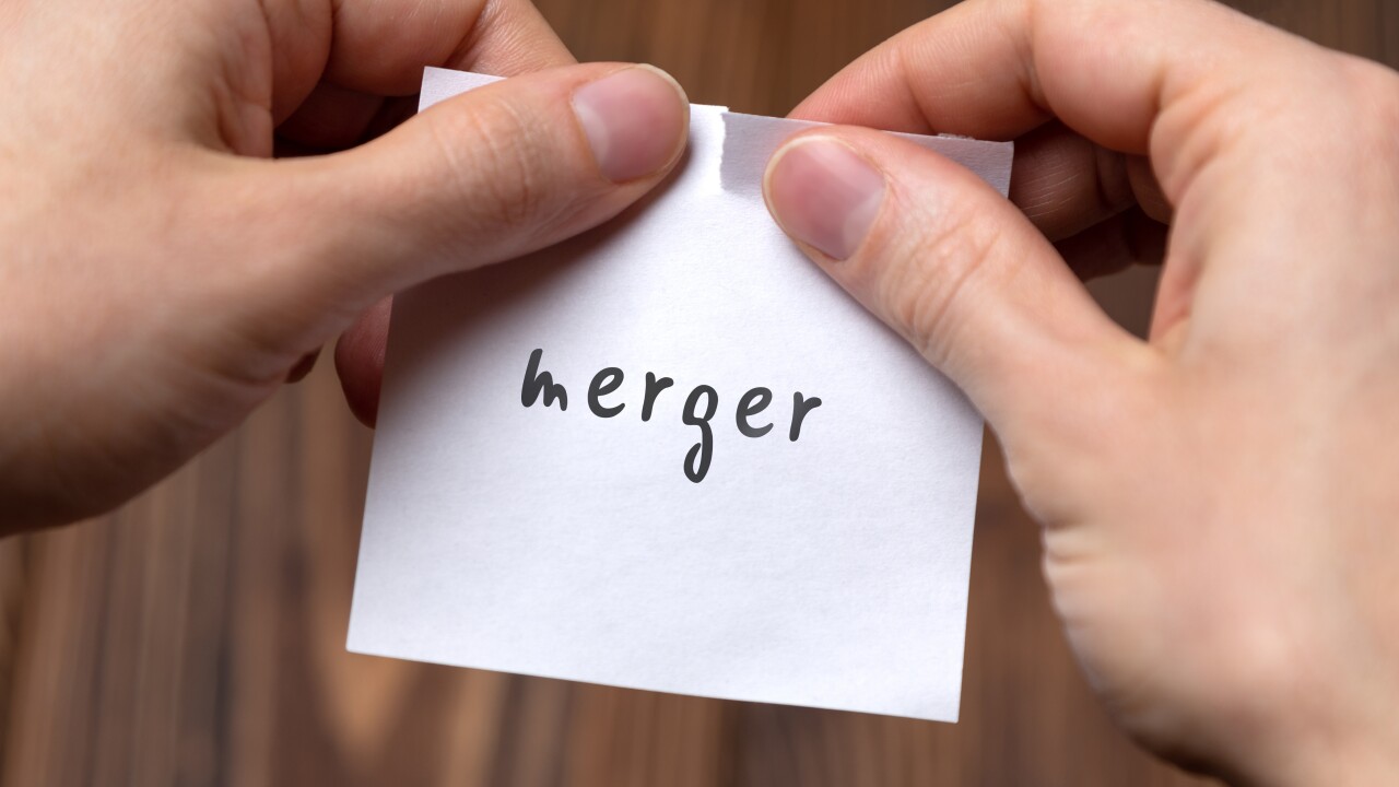 Hands of a man tearing a piece of paper with inscription merger