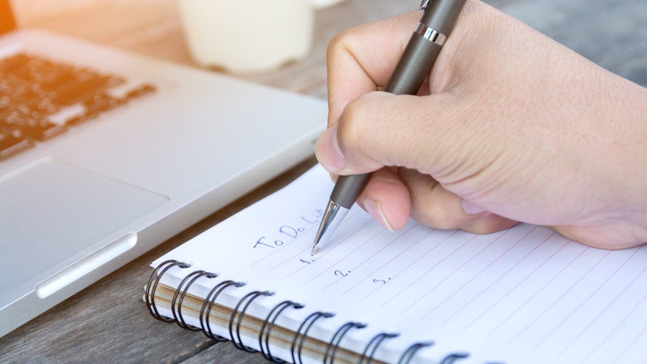 Person writing out their to do list in a notebook