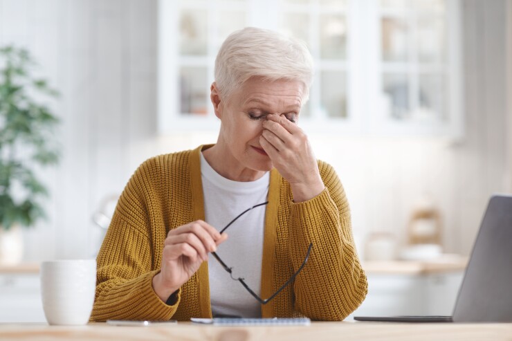 Older woman looking stressed while typing at her computer