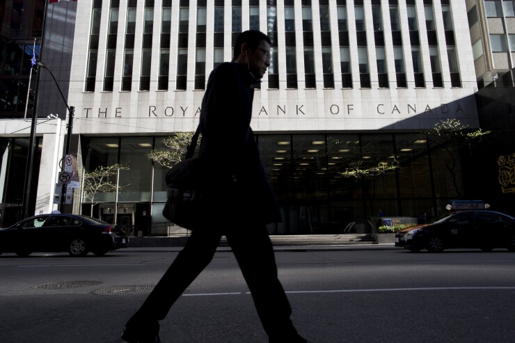 A pedestrian passes in front of a Royal Bank of Canada building in Toronto.
