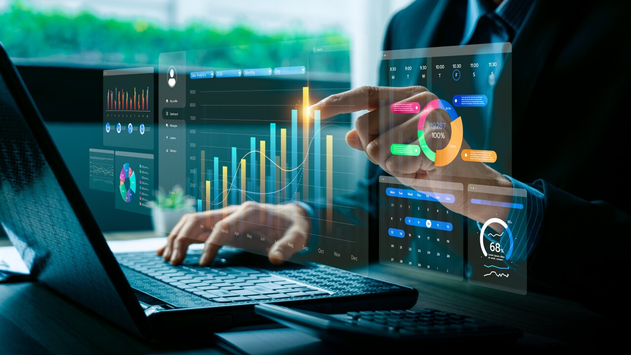 A person using a laptop while interacting with several holographic charts.