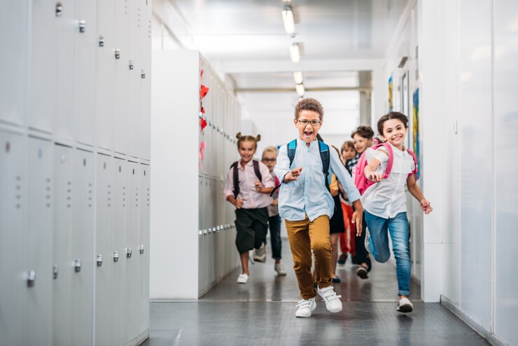 Young children running down their school hall.