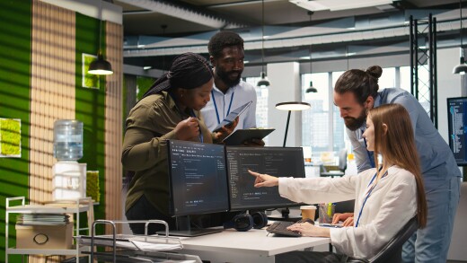 A group of people working around two monitors