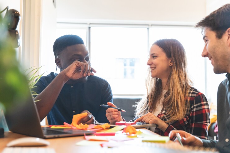 Young workers sit together at a table laughing.
